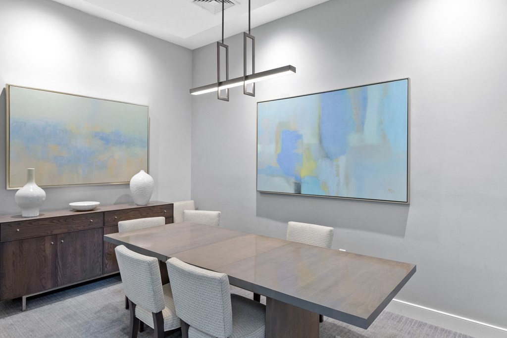 a dining room with a wooden table and white chairs and two paintings on the wall at Cirrus Apartments, Massachusetts