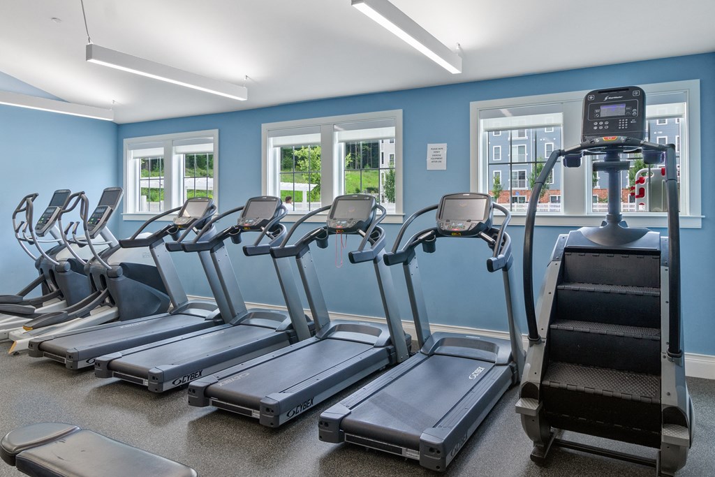 a row of treadmills and elliptical trainers in a fitness room at Cirrus Apartments, Ashland, MA, 01721
