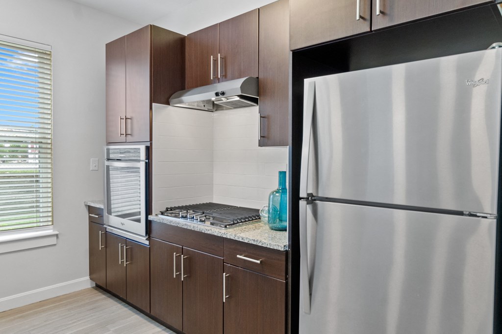 a kitchen with brown cabinets and stainless steel appliances at Cirrus Apartments, Ashland, 01721