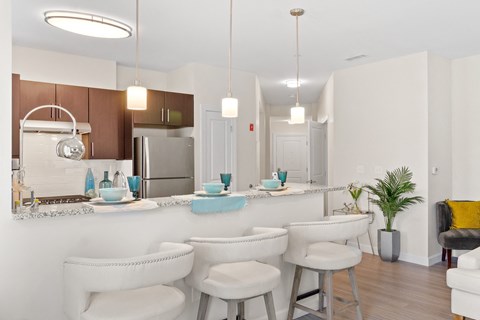 an open kitchen and dining area with white chairs and a counter top with blue bowls
