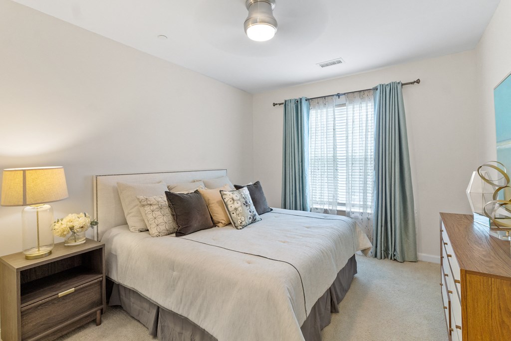 a bedroom with a bed and a dresser with a lamp at Cirrus Apartments, Ashland, Massachusetts