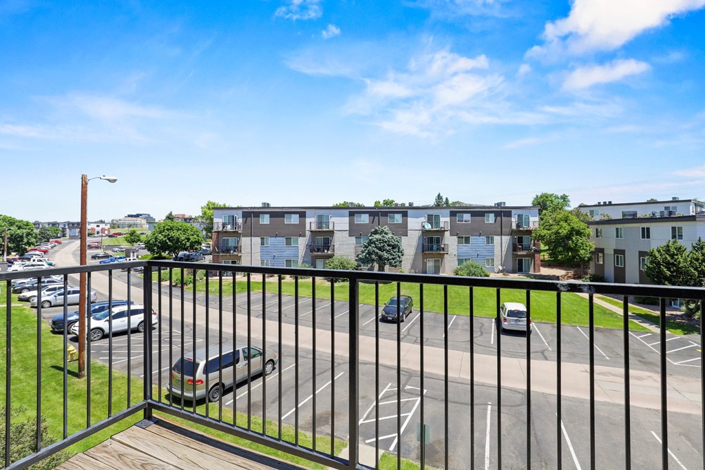 a balcony with a black railing overlooking a parking lot