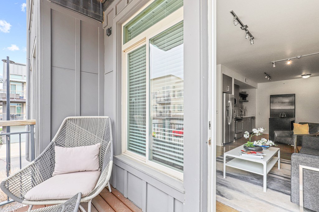 a small balcony with a chair and a coffee table