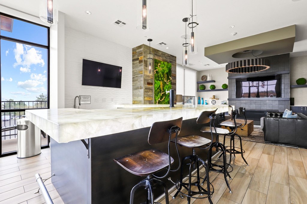 a kitchen with a long island with a marble countertop and four stools at Union West Apartments, Colorado