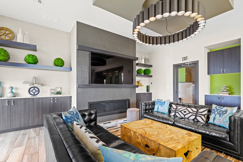 a living room with black leather couches and a wooden coffee table at Union West Apartments, Colorado 80228