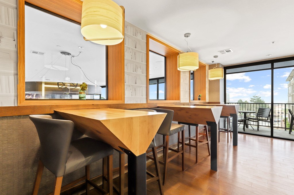 a dining area with wooden tables and chairs and a large window with a view of the outdoors at Union West Apartments, Lakewood, 80228
