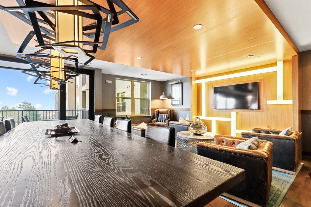 a long table with chairs and a tv in a room with a couch and a chair at Union West Apartments, Lakewood, Colorado