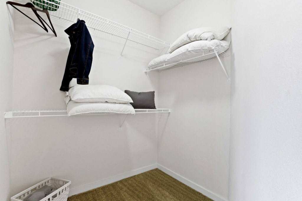 a room with a white wall and a white shelf with white pillows and a black jacket