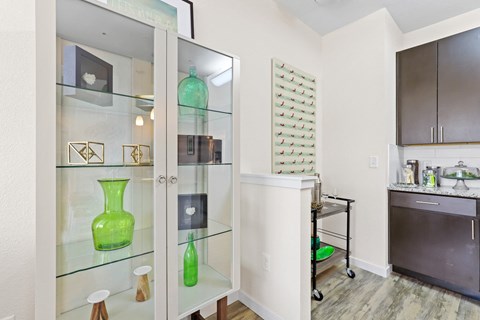 a glass display case with green vases in a kitchen at WestLink at Oak Station, Lakewood, Colorado
