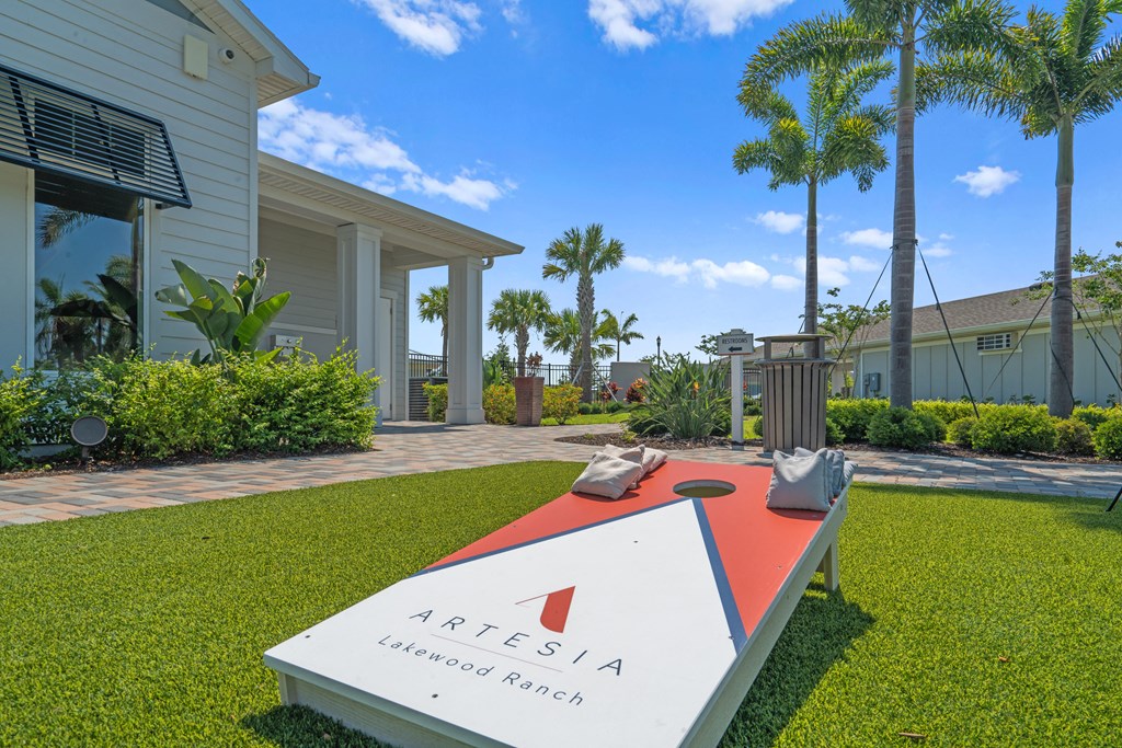 a sign sits on the grass in front of a house with palm trees at Artesia at Lakewood Ranch Apartments, Bradenton, FL, 34211