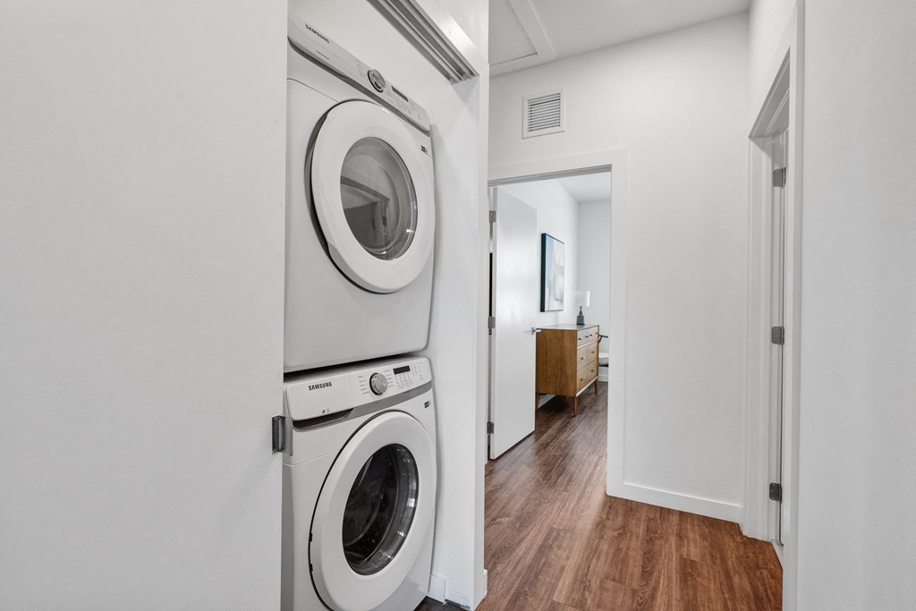 a white washer and dryer in a white laundry room with a wooden floor at Odyssey, Florida, 33905