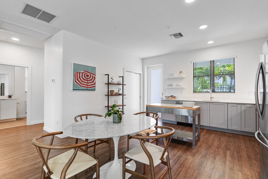 a dining room with a marble table and four chairs and a kitchen with a sink at Odyssey, Florida