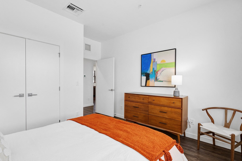 bedroom with white walls and a white bed with an orange blanket at Odyssey, Fort Myers, FL, 33905