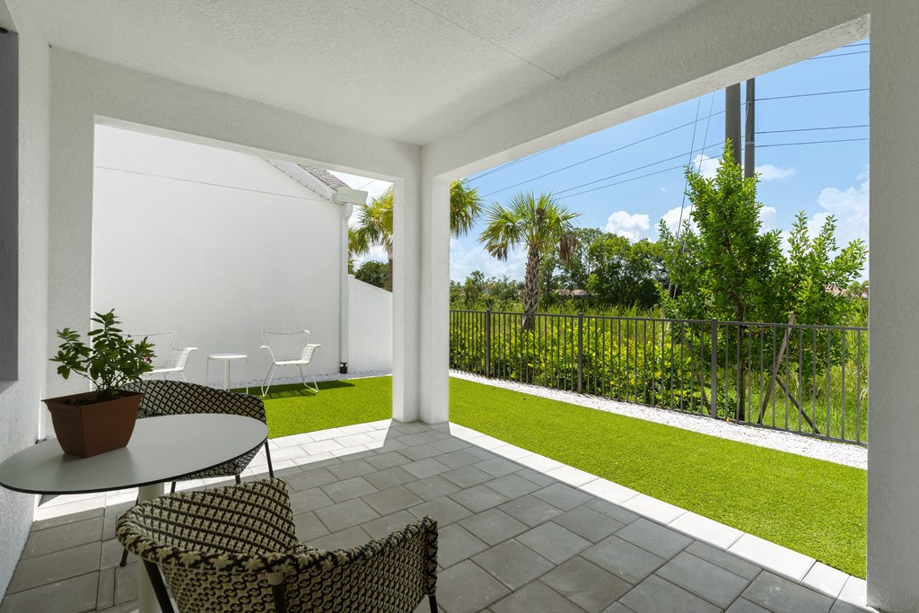 a patio with two chairs and a table and a lawn at Odyssey, Florida, 33905