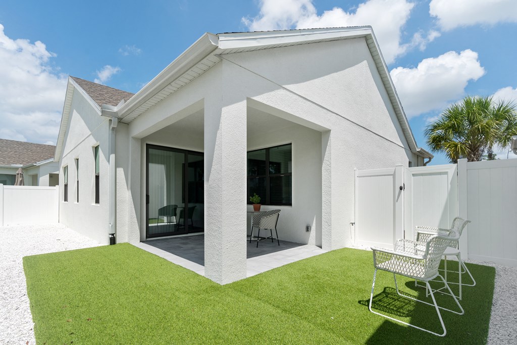 the exterior of a white house with a lawn and two chairs at Odyssey, Florida