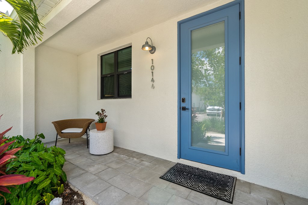 the front porch of a house with a blue door at Odyssey, Fort Myers, FL, 33905