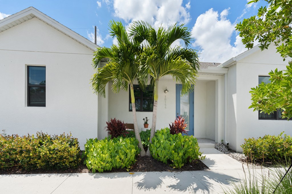 a white house with a palm tree in front of it at Odyssey, Florida, 33905