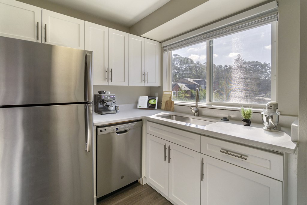 a kitchen with white cabinets and a large window