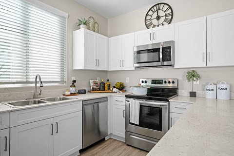 A modern kitchen with white cabinets and stainless steel appliances.