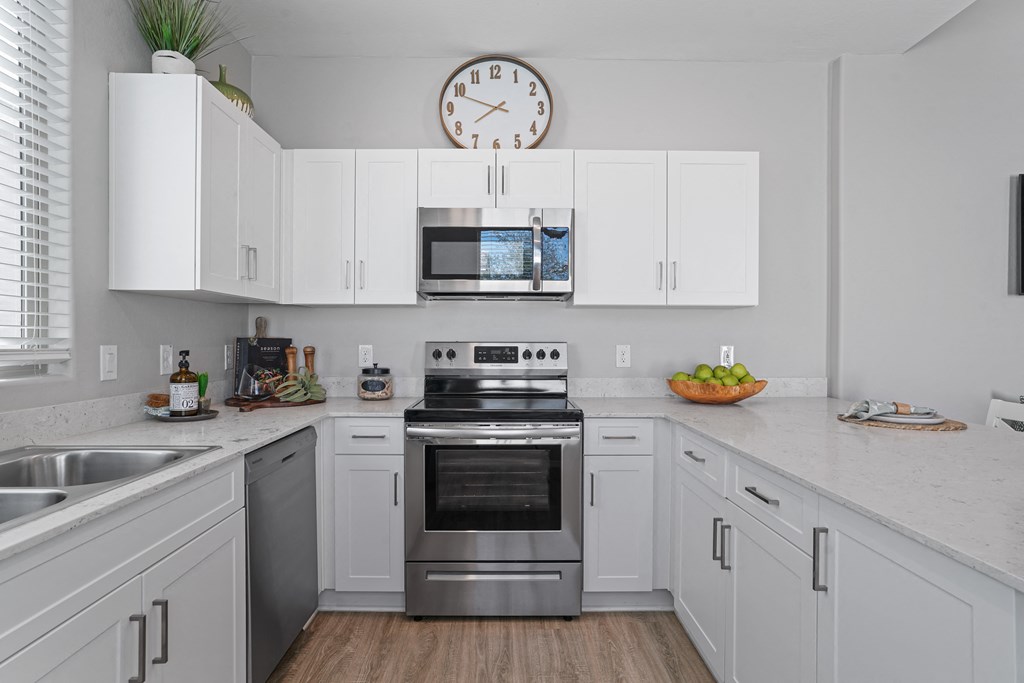 a kitchen with white cabinets and stainless steel appliances and a clock at Sienna at South Mountain Apartments, Laveen
