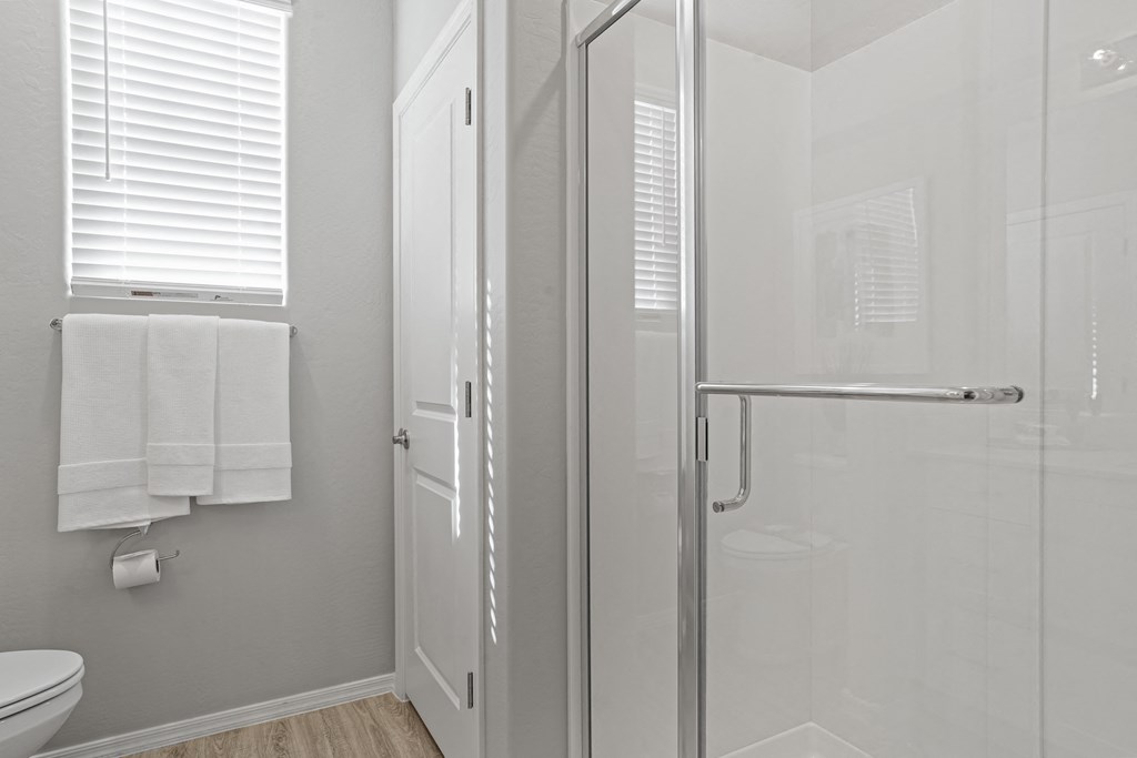 a white bathroom with a glass shower and a white toilet at Sienna at South Mountain Apartments, Laveen, AZ