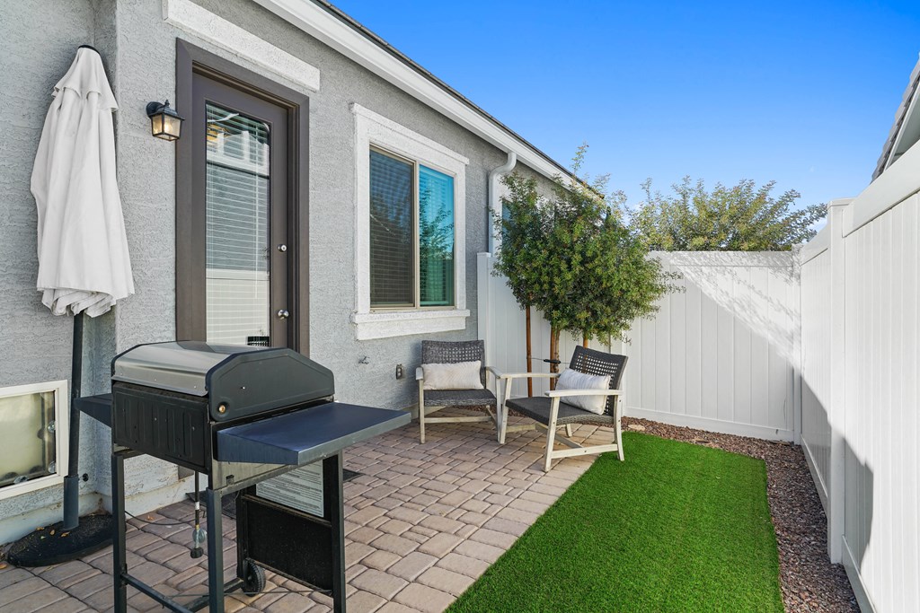 a backyard with a grill and chairs and a lawn at Sienna at South Mountain Apartments, Laveen, Arizona