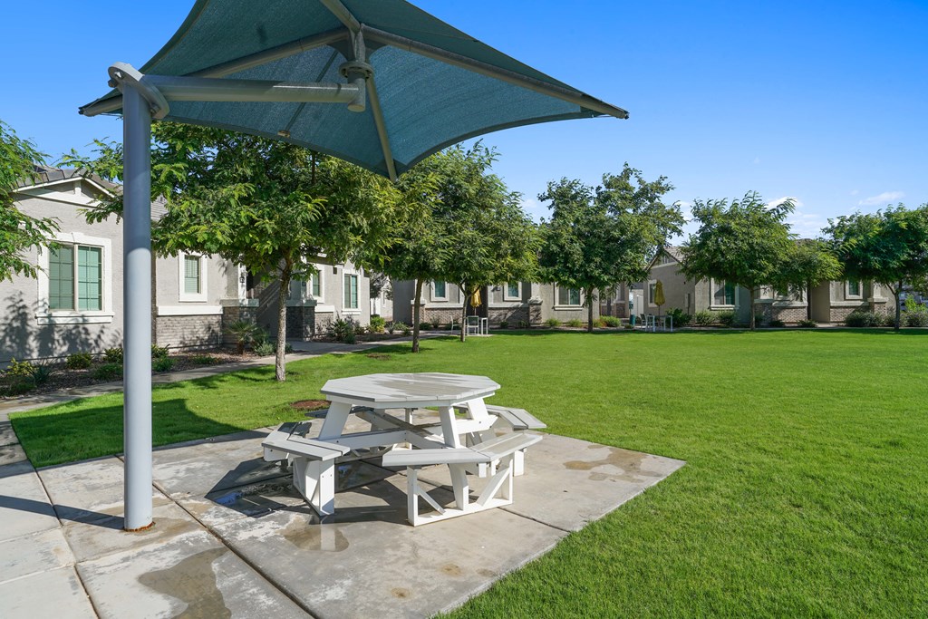 a picnic table with an umbrella on the grass at Sienna at South Mountain Apartments, Laveen