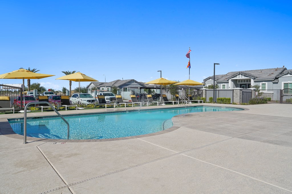 a swimming pool with yellow umbrellas in front of apartment buildings at Sienna at South Mountain Apartments, Laveen, AZ, 85339