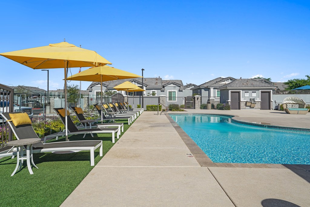 a pool with lounge chairs and umbrellas next to a pool at Sienna at South Mountain Apartments, Arizona, 85339