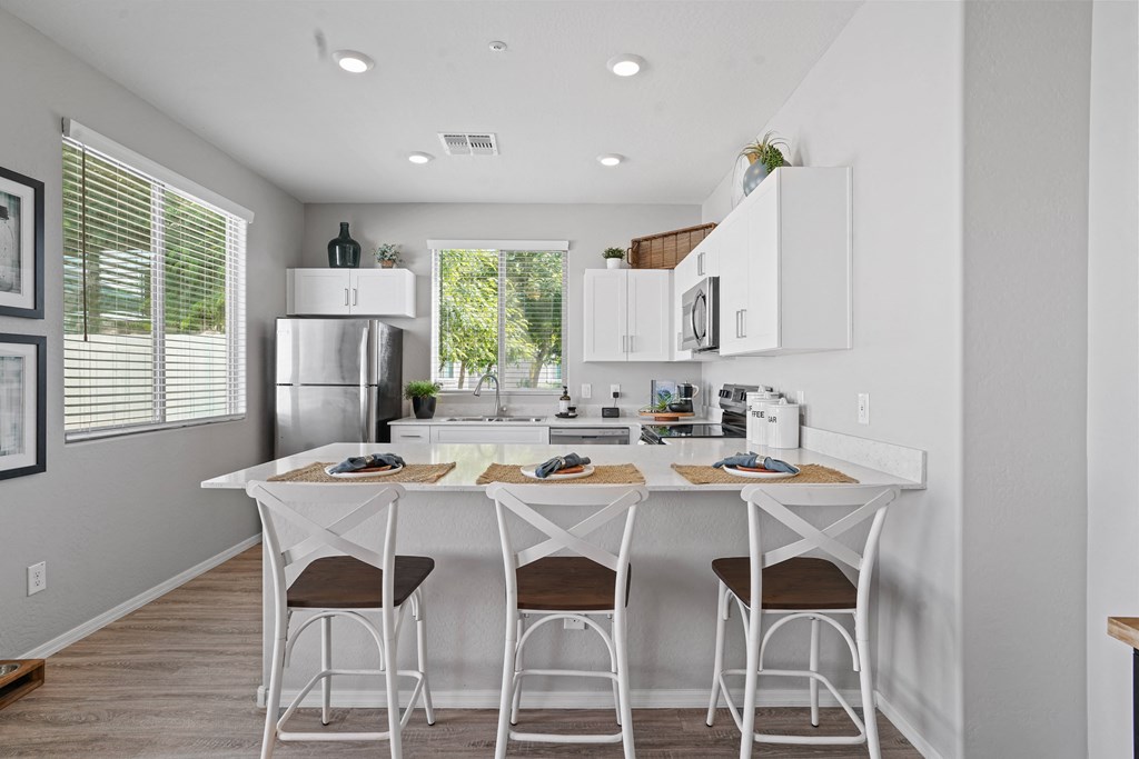 a kitchen with a white island with three stools at Sienna at South Mountain Apartments, Arizona, 85339