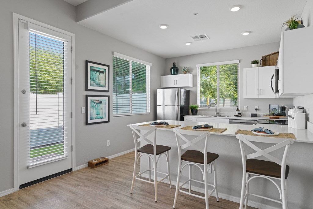 a kitchen with a bar and stools and a refrigerator at Sienna at South Mountain Apartments, Arizona