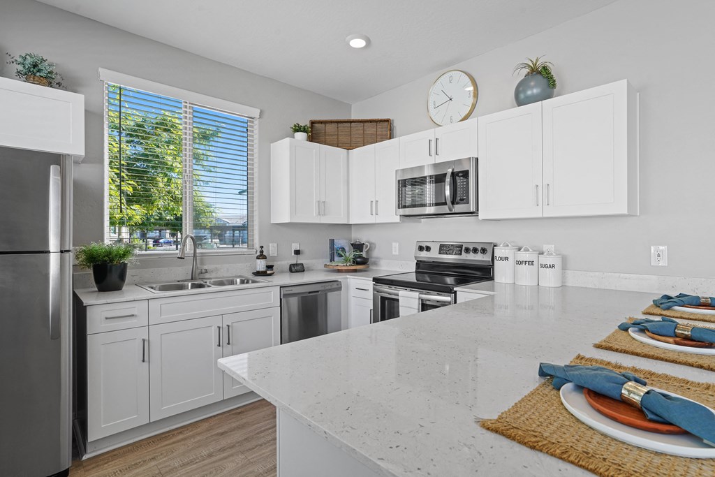 a large kitchen with white cabinets and stainless steel appliances at Sienna at South Mountain Apartments, Laveen, AZ