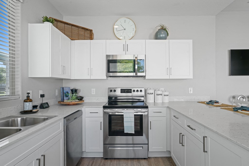 a kitchen with white cabinets and stainless steel appliances and a clock at Sienna at South Mountain Apartments, Laveen, AZ, 85339