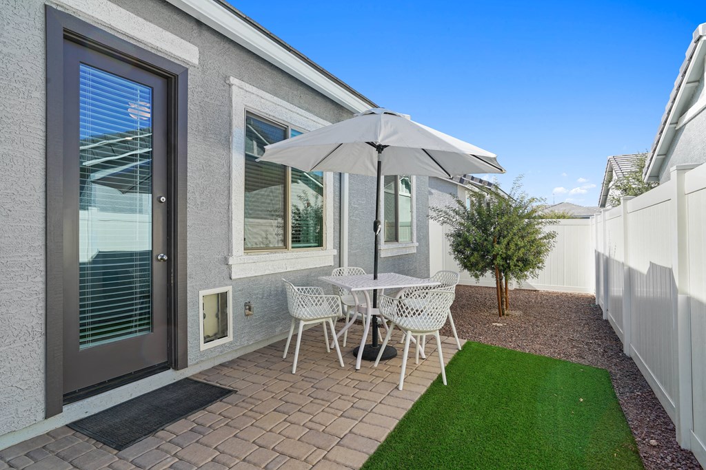 patio with stone and turf and table with chairs and umbrella at Sienna at South Mountain Apartments, Laveen