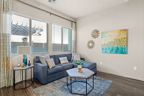 A living room with a grey couch, a small table, and a painting on the wall.