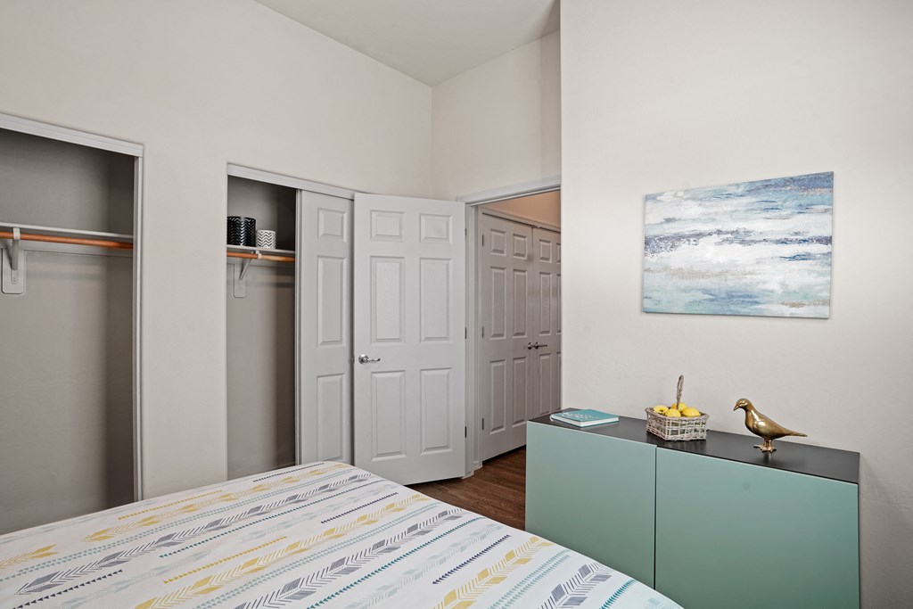 a bedroom with a bed and a closet and a painting on the wall