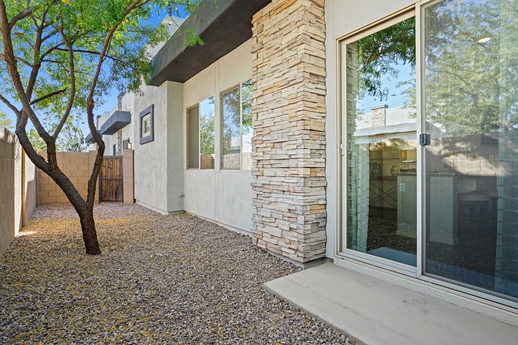 a patio with a tree and a white house with glass doors