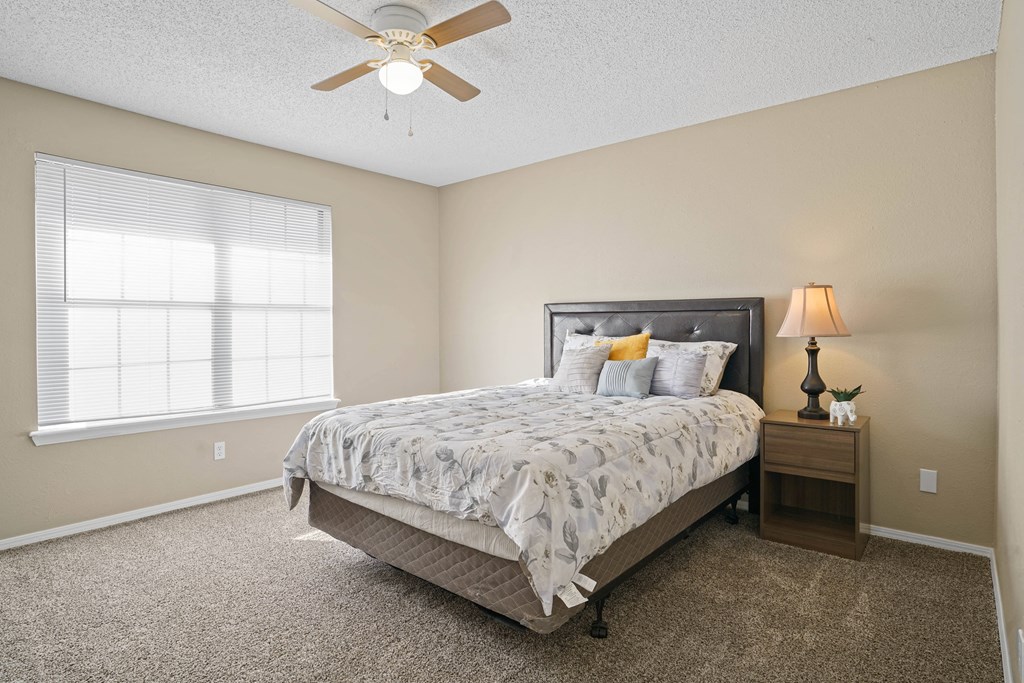 bed with white blanket and pillows next to large window