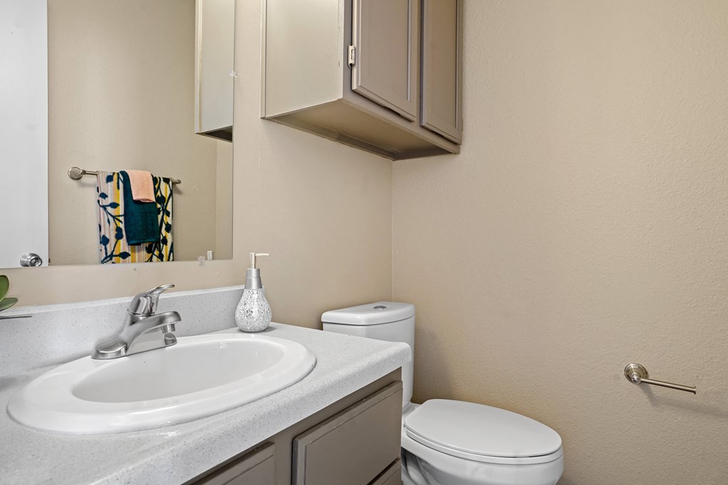 bathroom with brown cabinets, white sink and toilet