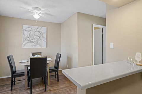a dining room and kitchen with a table and chairs and a ceiling fan