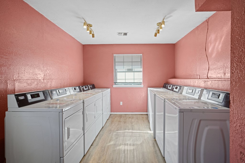 washers and dryers in room with window and pink walls