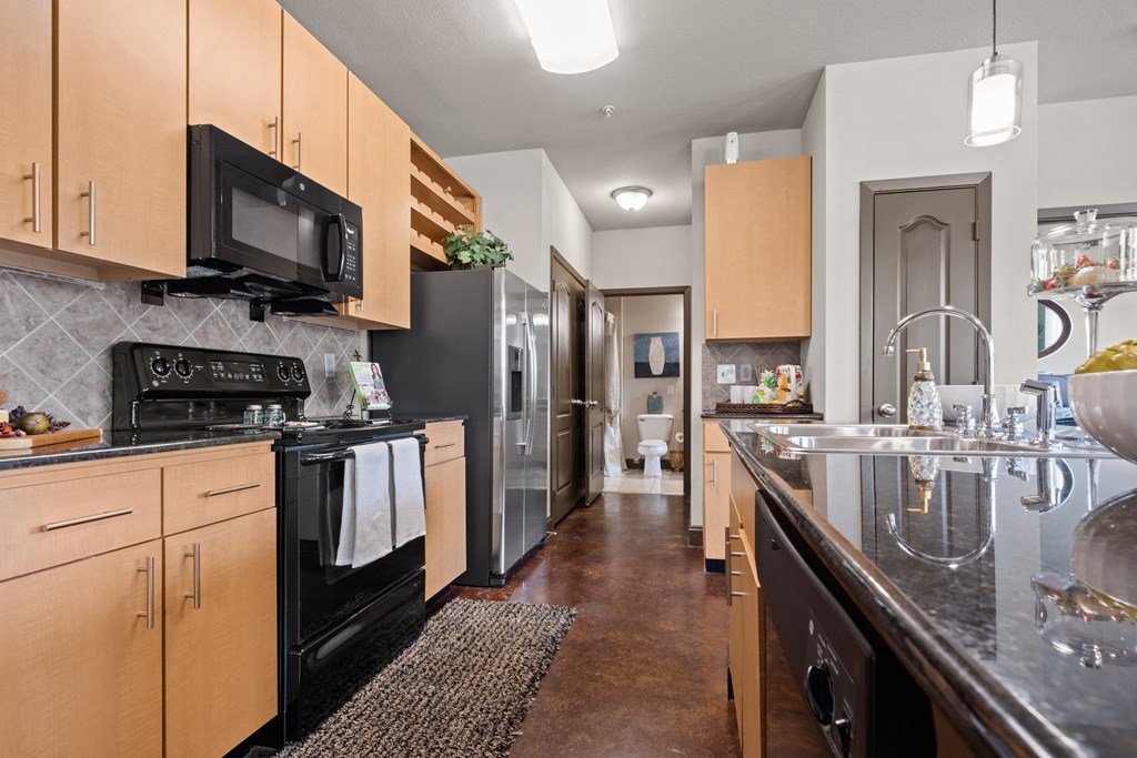 a kitchen with stainless steel appliances and wooden cabinets at The Millennium Towne Center Apartments, Baton Rouge