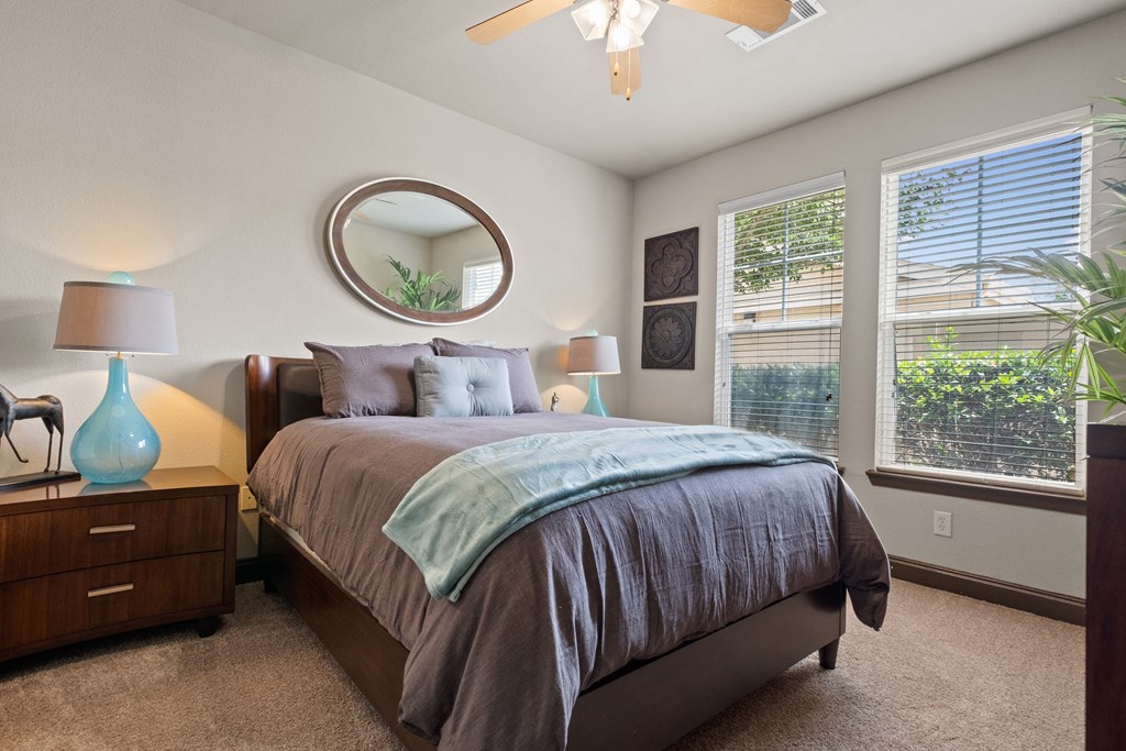 a bedroom with a large bed and two windows at The Millennium Towne Center Apartments, Louisiana 70806