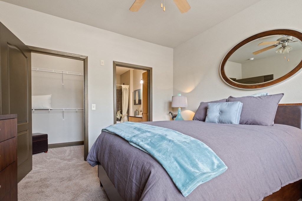 a bedroom with a bed and a closet and a mirror at The Millennium Towne Center Apartments, Baton Rouge, LA, 70806