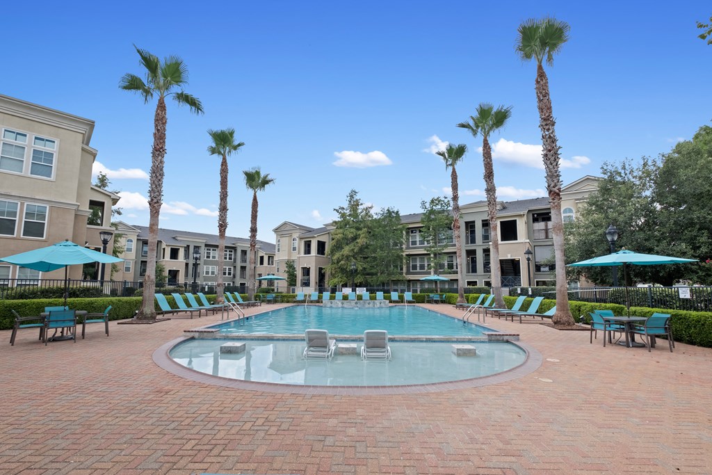 a large pool with chairs and umbrellas in front of apartment buildings at The Millennium Towne Center Apartments, Baton Rouge, LA, 70806