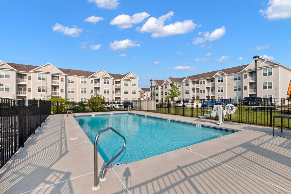 a swimming pool with an apartment building in the background at The Landing Apartment , Hazlet