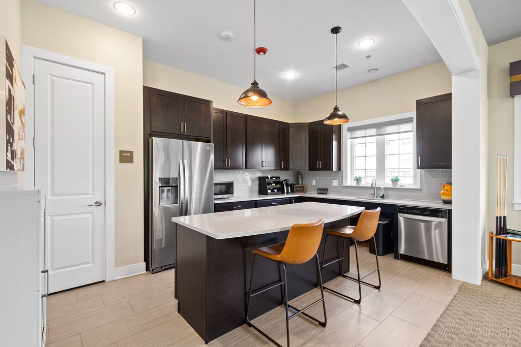 a kitchen with a large island with three chairs and a stainless steel refrigerator at The Landing Apartment , Hazlet, 07730
