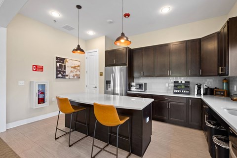 a kitchen with a large island with two orange chairs