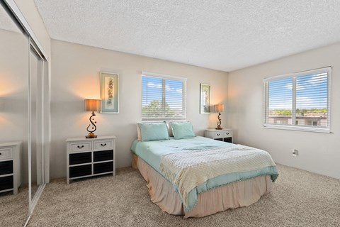 a bedroom with a bed and two windows at Park 88 Apartments, Thornton, CO