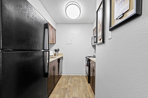 a kitchen with a refrigerator freezer and a stove top oven at Park 88 Apartments, Thornton, CO